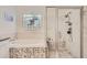 Beautiful bathroom featuring mosaic tile accents, soaking tub, glass shower and block window at 7360 S Owens Ct, Littleton, CO 80127