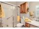 Well-lit bathroom with a shower featuring glass doors, oak cabinets, and warm yellow towels at 7360 S Owens Ct, Littleton, CO 80127