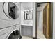 Bathroom with washer and dryer next to a bathroom with a sink and mirror next to an open door to a shower at 54 S Emerson St # 4, Denver, CO 80209