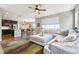 Open-concept living room with a ceiling fan, large windows, hardwood floors, and a modern, neutral-toned sectional sofa at 18083 Telford Ave, Parker, CO 80134