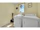 Bright laundry room with modern white washer and dryer, utility vacuum, and decorative wall art at 5722 S Flat Rock Way, Aurora, CO 80016