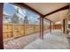 Covered back patio features wood beams and fencing with a rock landscape design at 11946 E Maple Ave, Aurora, CO 80012