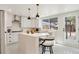 Bright, all-white kitchen with island, sleek bar stools, and stainless-steel appliances is perfect for modern living at 1130 S Harrison St, Denver, CO 80210