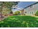 Spacious backyard with lush green grass and mature trees offers privacy and shade at 8416 S Reed St, Littleton, CO 80128