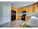 Bright kitchen features wood cabinets, black appliances, and gray wood-look flooring at 8416 S Reed St, Littleton, CO 80128