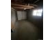 Unfinished basement garage with exposed wooden beams, concrete walls, and a small window for natural light at 8220 E 104Th Way, Henderson, CO 80640