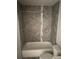 Bathroom with a shower-tub combo, gray marble-style tiles, and a modern shower head at 8220 E 104Th Way, Henderson, CO 80640