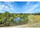 A tranquil pond view through a wooden fence with plenty of trees and a walking path at 12793 Leyden St # D, Thornton, CO 80602