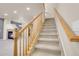 Carpeted stairs with wood railing leading to the upper level, showcasing the open-concept design at 12793 Leyden St # D, Thornton, CO 80602
