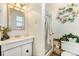 Bright bathroom with a floral wreath, white vanity, and shower with a chrome rack at 4295 S County Road 193, Byers, CO 80103