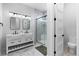 Modern bathroom with double vanity, sliding glass shower door, white tile, and a toilet in the corner at 12215 Viewpoint Dr, Lakewood, CO 80401