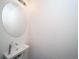 A well-lit powder room featuring a modern round mirror and wall-mounted sink at 46505 Avery Ln, Commerce City, CO 80022