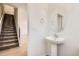 Powder room with modern fixtures, a pedestal sink, a round mirror, and easy access to the main floor at 6562 Arbor Blvd # 1, Thornton, CO 80602