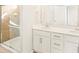 Bright bathroom featuring double sink vanity, shower with glass door and tan tiling, bright lighting, and modern fixtures at 741 N Tibet St, Aurora, CO 80018