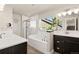Bright bathroom showcasing a soaking tub with marble tile, double sink vanity, and a glass-enclosed shower at 208 Dorothy Dr, Berthoud, CO 80513