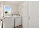 Well-organized laundry room with washer, dryer, storage cabinets, and a bright window at 208 Dorothy Dr, Berthoud, CO 80513