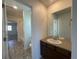 Bright bathroom with a dark wood vanity, large mirror, and tile flooring with a view into the combined shower and bath at 1055 Snowberry Ave, Elizabeth, CO 80107