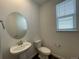 Modern powder bathroom with round mirror, toilet and sleek fixtures at 1055 Snowberry Ave, Elizabeth, CO 80107