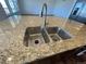 Close-up of the kitchen island's double sink with granite countertops and stainless steel faucet at 1055 Snowberry Ave, Elizabeth, CO 80107