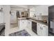 Well-lit kitchen with white cabinets and modern stainless steel appliances leads to staircase and living area at 6444 Silver Mesa Dr # A, Highlands Ranch, CO 80130