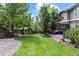 Expansive backyard with lush lawn, mature trees, storage shed, and a deck with a hot tub at 5301 Clovervale Cir, Highlands Ranch, CO 80130
