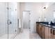 Modern bathroom features a glass shower, wood-look cabinets, and double sinks at 9052 Harlan St, Westminster, CO 80031
