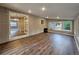 Bright living room with wood-look flooring, brick accent wall, and large windows at 6717 Lee St, Arvada, CO 80004