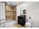 Cozy bathroom with tiled shower-tub combo, wood vanity, and a decorative mirror at 1832 W 36Th Ave, Denver, CO 80211