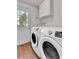 Bright laundry room with white cabinets, white washer and dryer, wood floor, and natural light at 4155 S Lipan St, Englewood, CO 80110