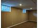 Unfinished basement with paneled walls, small windows, and neutral carpet at 1500 S Perry St, Denver, CO 80219
