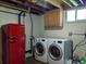 Basement laundry area features a modern washer and dryer, cabinet storage, and vintage red Galanz refrigerator at 1500 S Perry St, Denver, CO 80219