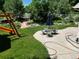 Lush backyard featuring a stone patio with seating, play structure and mature trees at 12705 Kalamath Ct, Westminster, CO 80234