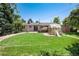 A lovely backyard with a lush green lawn, mature trees, and greenhouse providing an outdoor oasis for relaxation at 5067 S Mabre Ct, Littleton, CO 80123