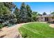 Lush backyard with a winding path, mature trees, a green lawn, and access to a covered patio at 5067 S Mabre Ct, Littleton, CO 80123
