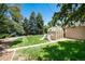 Spacious backyard featuring a green lawn, mature trees, and a greenhouse near the house at 5067 S Mabre Ct, Littleton, CO 80123