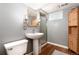 Updated bathroom featuring a pedestal sink, wood-look flooring, and a tiled shower at 5067 S Mabre Ct, Littleton, CO 80123
