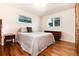 Sunlit bedroom featuring hardwood floors, a comfortable bed, and charming furnishings at 5067 S Mabre Ct, Littleton, CO 80123