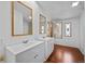 Bright bathroom featuring double vanity sinks, framed mirrors, and wood-look flooring at 5325 Allison St, Arvada, CO 80002