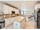 Bright kitchen with white cabinets, a center island, and stainless steel appliances with views into the living room at 8010 Raspberry Dr, Frederick, CO 80504