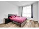 Bright bedroom featuring wood-look floors, a window with sheer curtains, and a sleek, modern platform bed at 5765 N Genoa Way # 1-103, Aurora, CO 80019