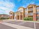 Charming condo building with brick and siding, balconies, manicured bushes, and paved parking at 5765 N Genoa Way # 1-103, Aurora, CO 80019