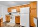 Well-lit kitchen featuring wooden cabinets, white appliances and laminate flooring at 5765 N Genoa Way # 1-103, Aurora, CO 80019