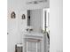 Bright bathroom featuring a vanity with a large mirror, vanity seat, and decorative wooden wall hangings at 3981 S Boston St, Denver, CO 80237
