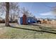 Backyard featuring blue house, brick patio, and fire pit with chairs and a green lawn at 4260 Newland St, Wheat Ridge, CO 80033