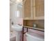 Bathroom featuring pedestal sink, pink walls, and a wood cabinet above the toilet at 4260 Newland St, Wheat Ridge, CO 80033