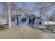 Inviting blue single-story home with mature trees, white picket fence and paved driveway at 4260 Newland St, Wheat Ridge, CO 80033