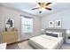 A well-staged bedroom featuring neutral tones, stylish furnishings, a ceiling fan, and a bright window at 5872 W Asbury Pl, Lakewood, CO 80227