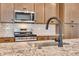Close-up of the kitchen featuring stainless steel appliances, granite countertops, and tiled backsplash at 3318 N Haleyville Ct, Aurora, CO 80019