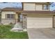 Close up of a tan two-story home with brick accents, well-manicured lawn, and an attached two-car garage at 9544 Josephine St, Thornton, CO 80229
