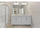 Bright bathroom featuring a double sink vanity, framed mirror, and glass enclosed shower at 13497 Valentia St, Thornton, CO 80602